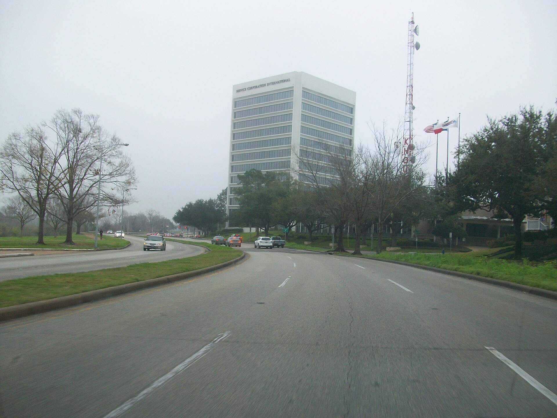 Allen Parkway beside trees and Houston office buildings