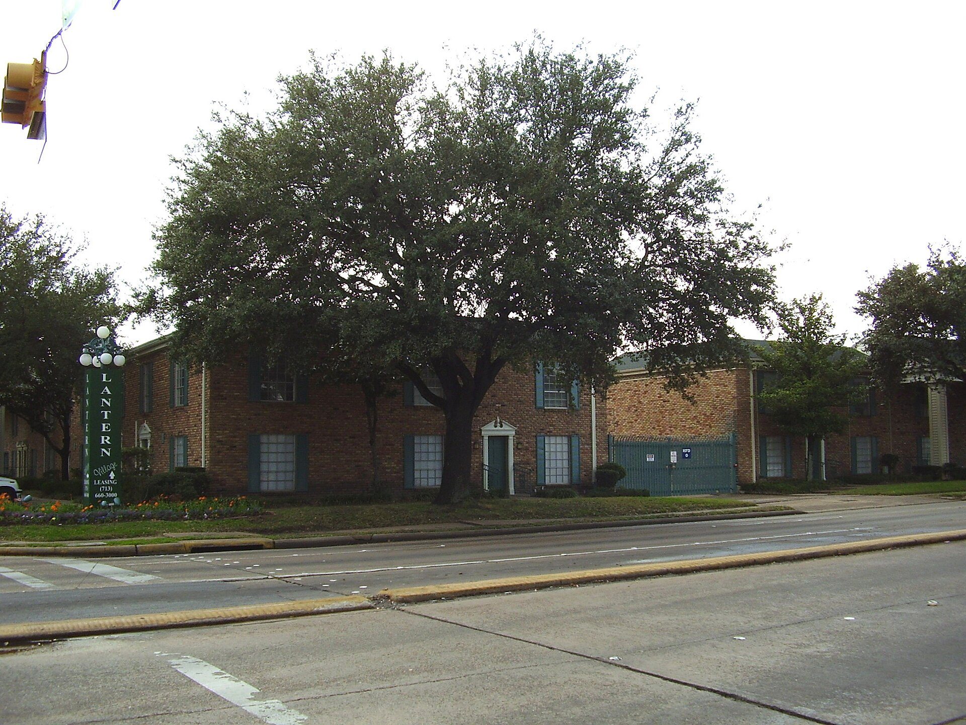 Tree-shaded apartment buildings at Lantern Village in Gulfton