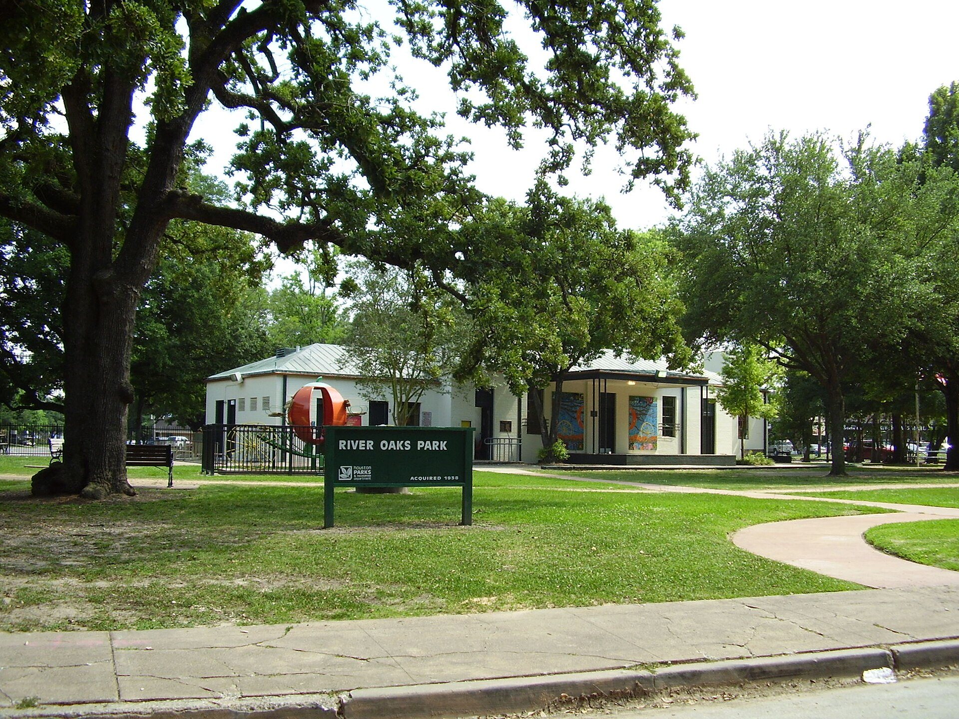 Tree-shaded lawn and building at River Oaks Park