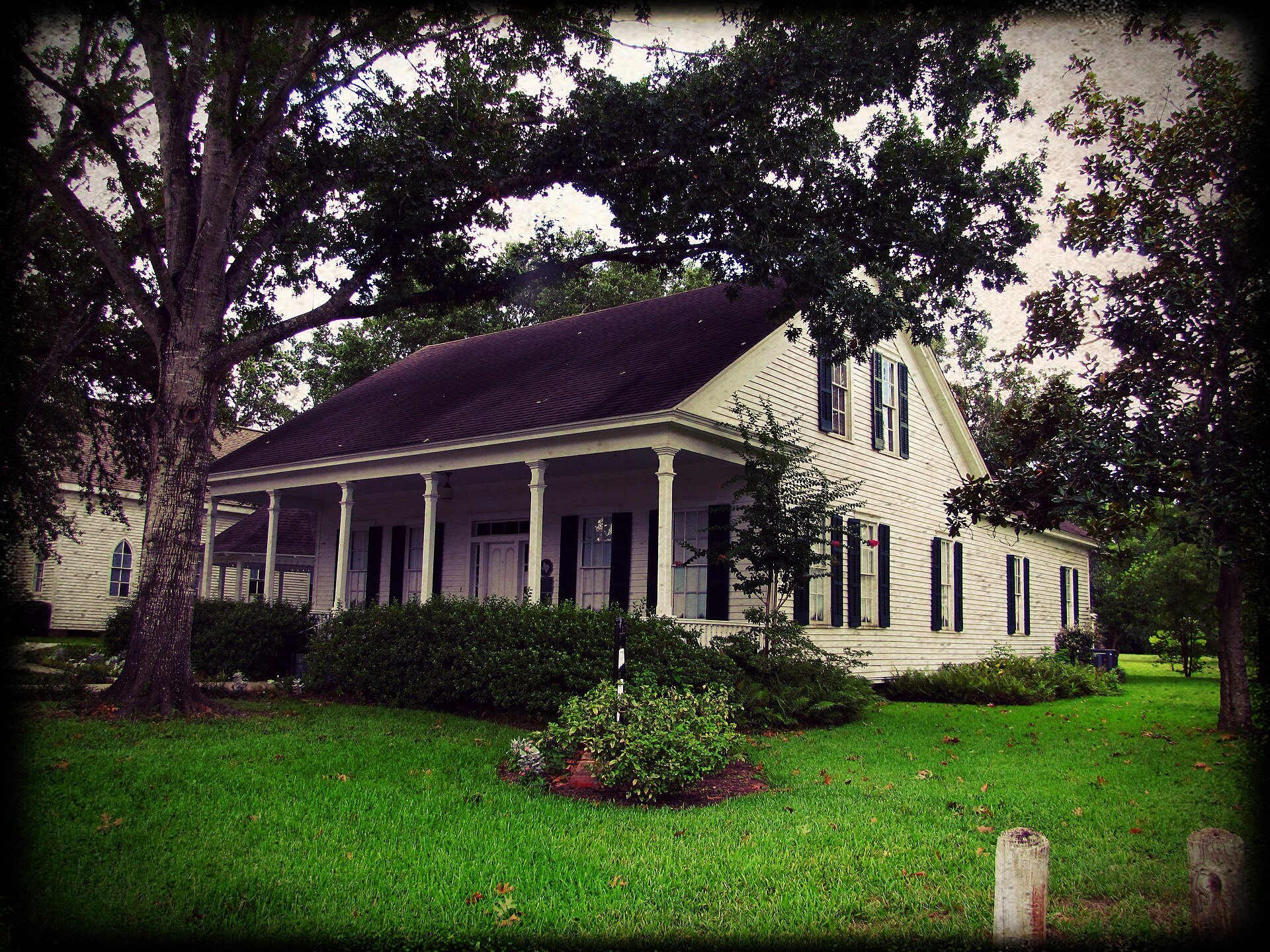 Historic Griffin House beneath mature trees in Tomball